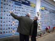 Japanese Foreign Minister Takeshi Iwaya, right, and Ukrainian Foreign Minister Andriiy Sybiha look at photos of fallen soldiers Saturday after a flower-laying ceremony at a memorial wall in Kyiv, Ukraine.