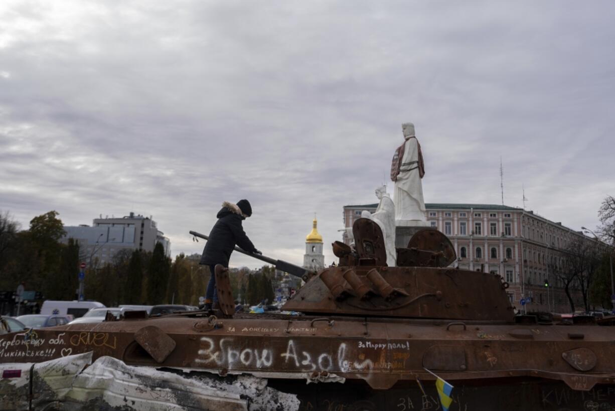 A boy stands on Russian burned APC in central Kyiv, Ukraine, Tuesday, Nov. 5, 2024.