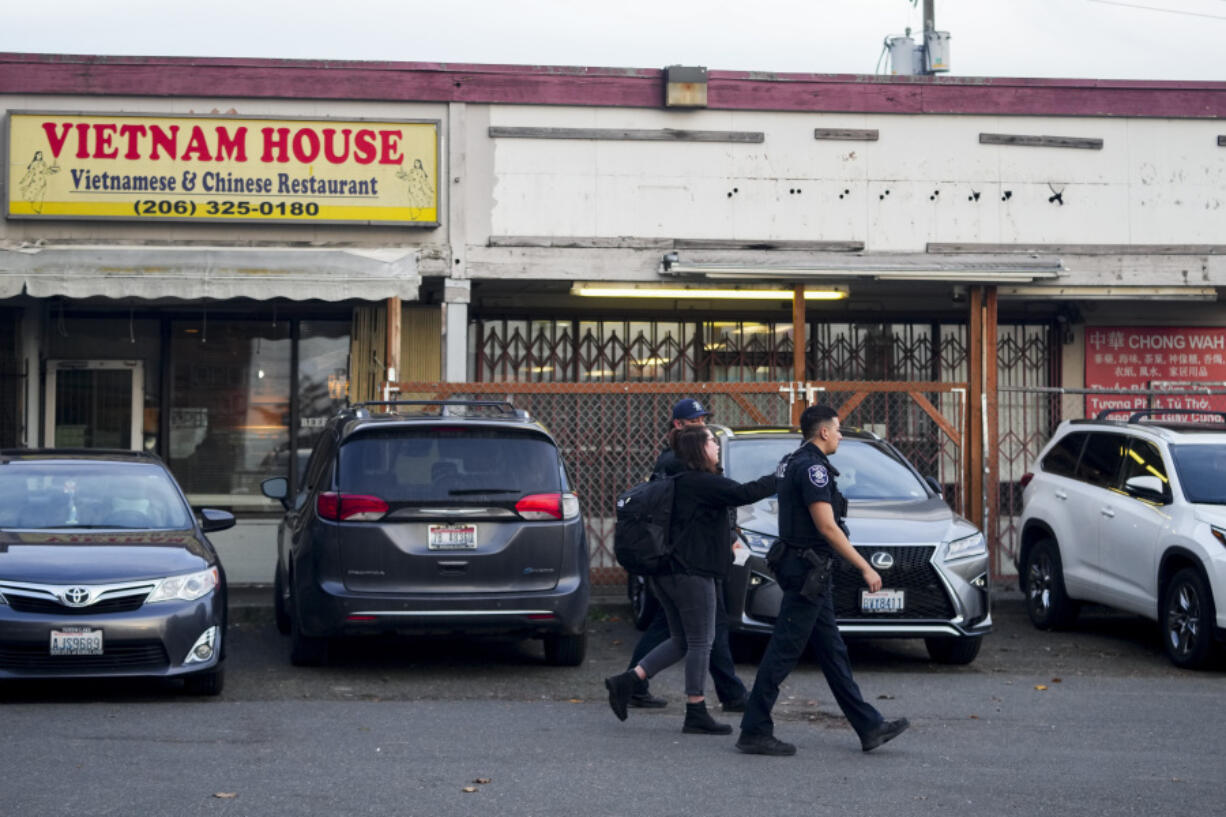 Police officers gather security camera footage from nearby businesses after multiple people were stabbed earlier in the area Friday, Nov. 8, 2024, in the Chinatown-International District in Seattle.