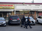 Police officers gather security camera footage from nearby businesses after multiple people were stabbed earlier in the area Friday, Nov. 8, 2024, in the Chinatown-International District in Seattle.