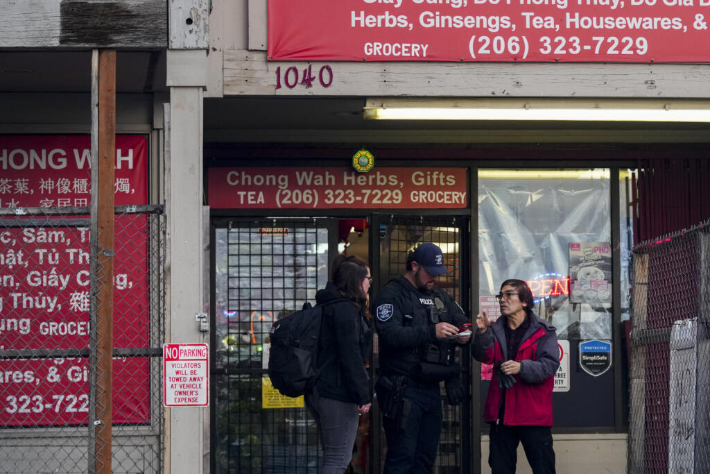 Police officers take a statement from a nearby business owner after multiple people were stabbed Friday, Nov. 8, 2024, in the Chinatown-International District in Seattle.