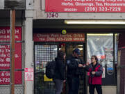 Police officers take a statement from a nearby business owner after multiple people were stabbed Friday, Nov. 8, 2024, in the Chinatown-International District in Seattle.