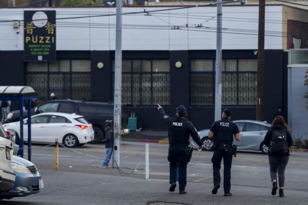 Police officers stand near the scene as they gather security camera footage after multiple people were stabbed in the area Friday, Nov. 8, 2024, in the Chinatown-International District in Seattle.