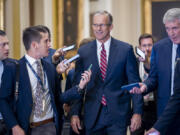 Senate Minority Whip John Thune, R-S.D., walks with reporters on the way to being elected to succeed longtime GOP leader Mitch McConnell of Kentucky, at the Capitol in Washington, Wednesday, Nov.