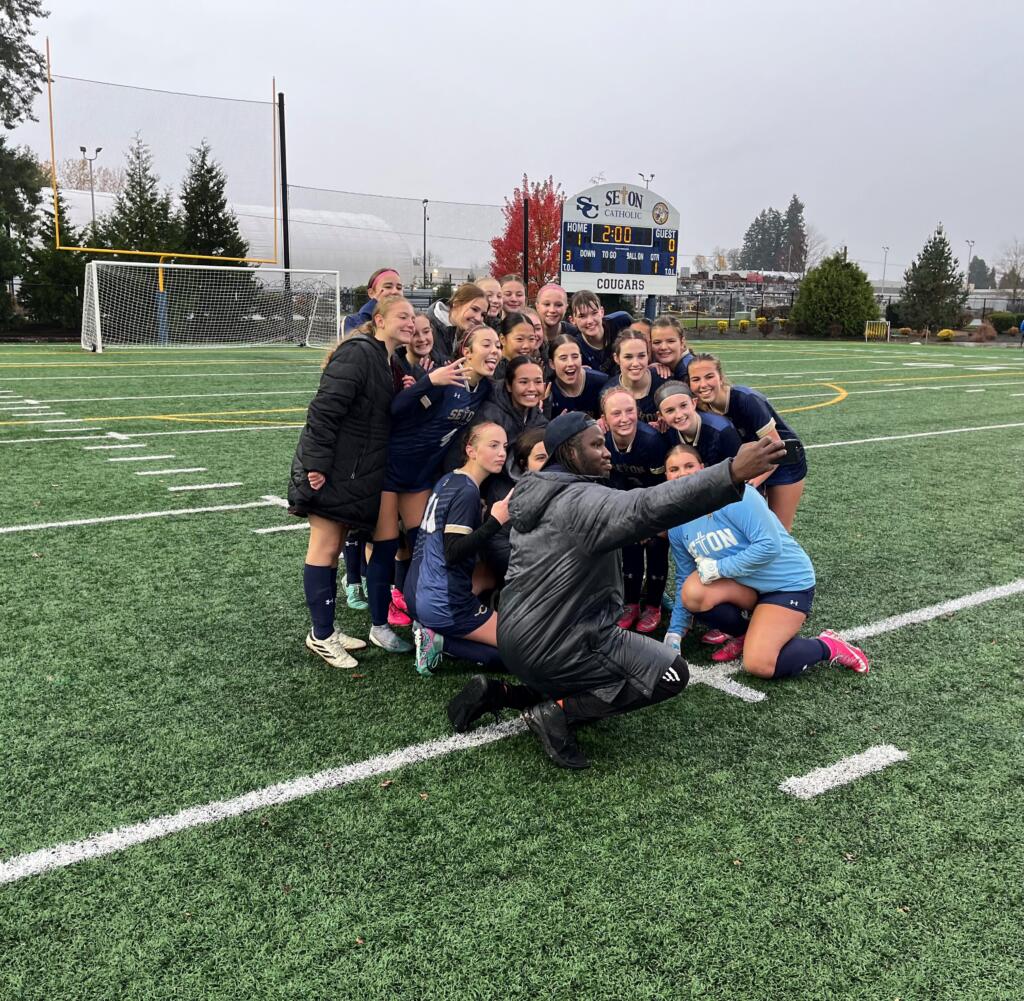 Seton Catholic players and coach Antonio Buckley pose for a photo after the Cougars' 1-0 win over The Bush School in the Class 1A girls soccer state quarterfinals on Saturday, Nov. 16, 2024, at Seton Catholic High School.