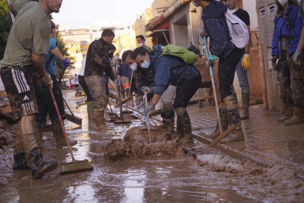 People sweep away mud during the clean up operation after flooding in Massanassa on the outskirts of Valencia, Spain, Wednesday, Nov. 6, 2024.