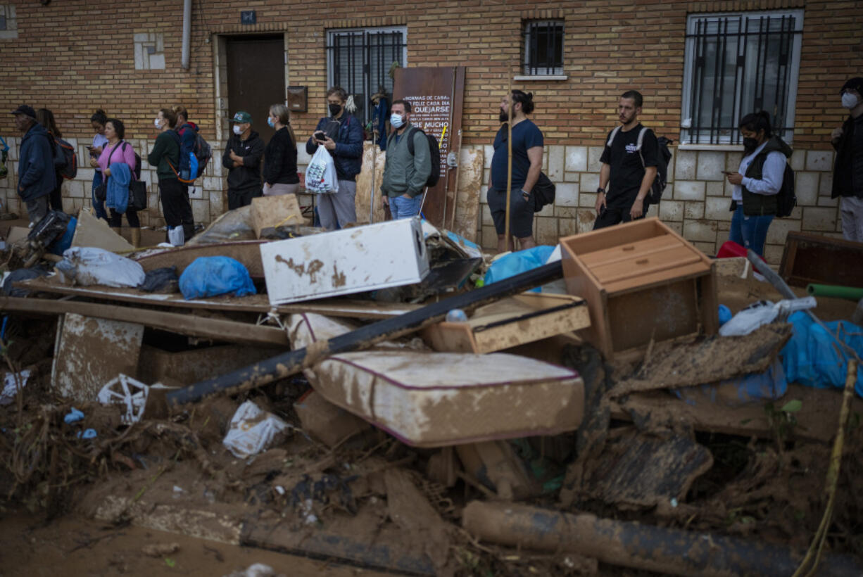 Residents wait for public transportation in an area, affected by floods, in Paiporta, Valencia, Spain, Tuesday, Nov. 5, 2024.