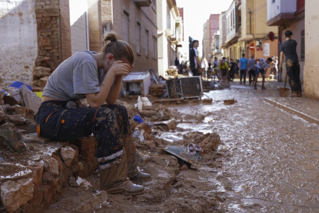 A woman rests as residents and volunteers clean up an area affected by floods in Paiporta, near Valencia, Spain, Friday, Nov. 1, 2024.