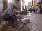 A woman rests as residents and volunteers clean up an area affected by floods in Paiporta, near Valencia, Spain, Friday, Nov. 1, 2024.