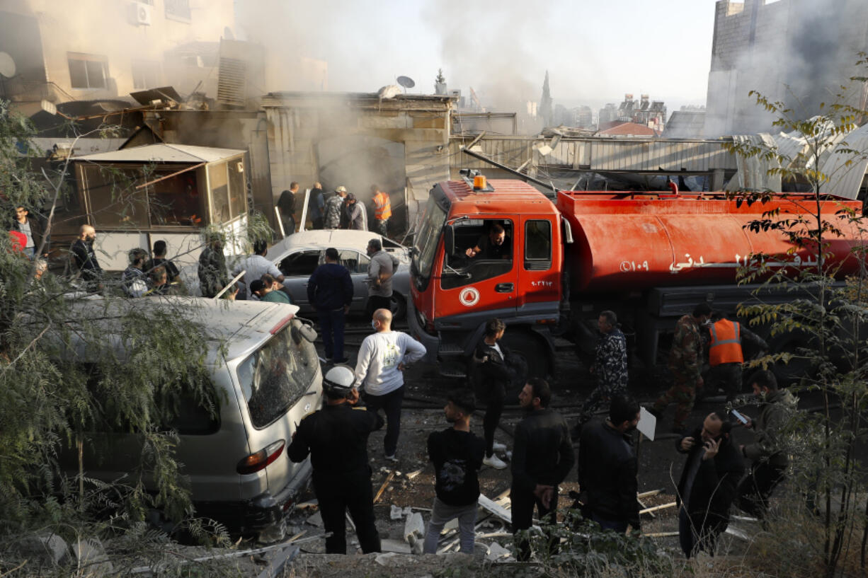 Firefighters and security officers gather at a destroyed building hit in an Israeli airstrike in Damascus, Syria, Thursday, Nov. 14, 2024.