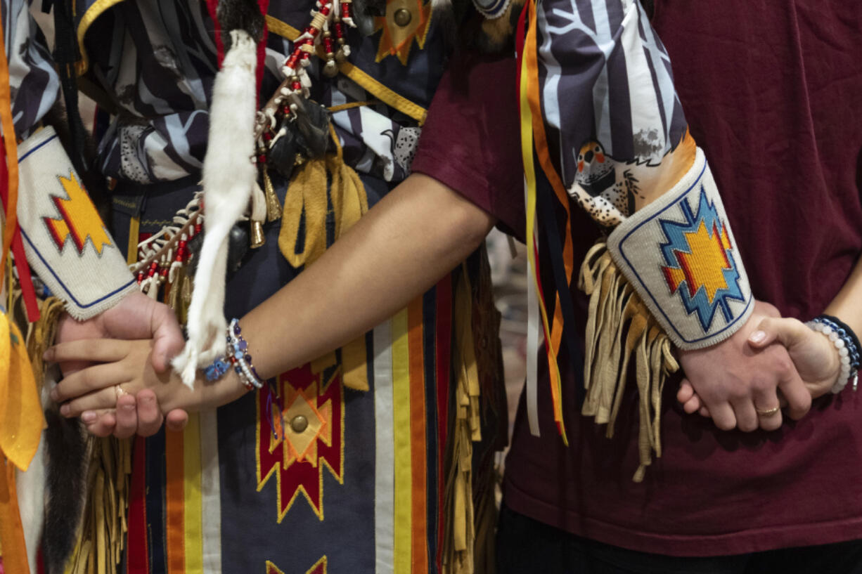 People hold hands during a dance at a powwow at Chinook Winds Casino Resort, Saturday, Nov. 16, 2024, in Lincoln City, Ore.