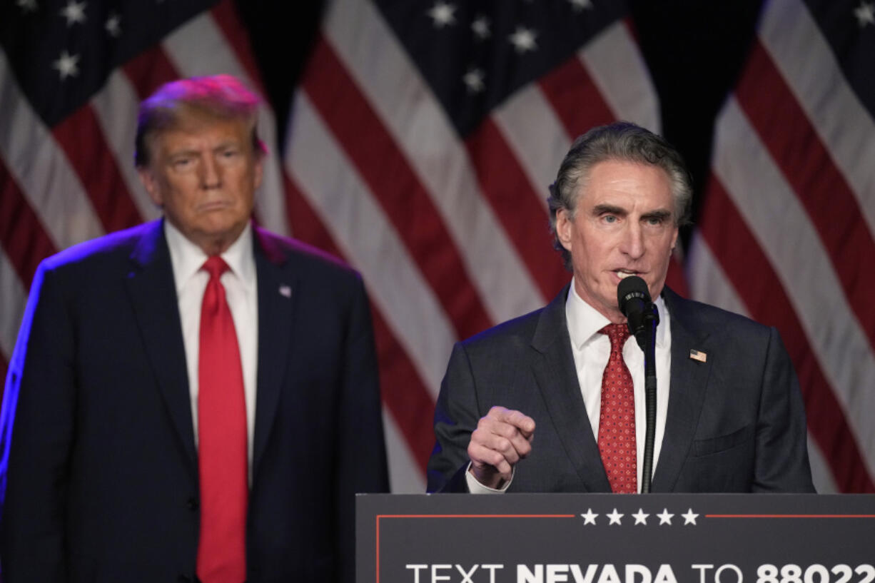 FILE - Republican presidential candidate former President Donald Trump listens as North Dakota Gov. Doug Burgum speaks at a caucus night rally in Las Vegas, Feb. 8, 2024. (AP Photo/Mark J.