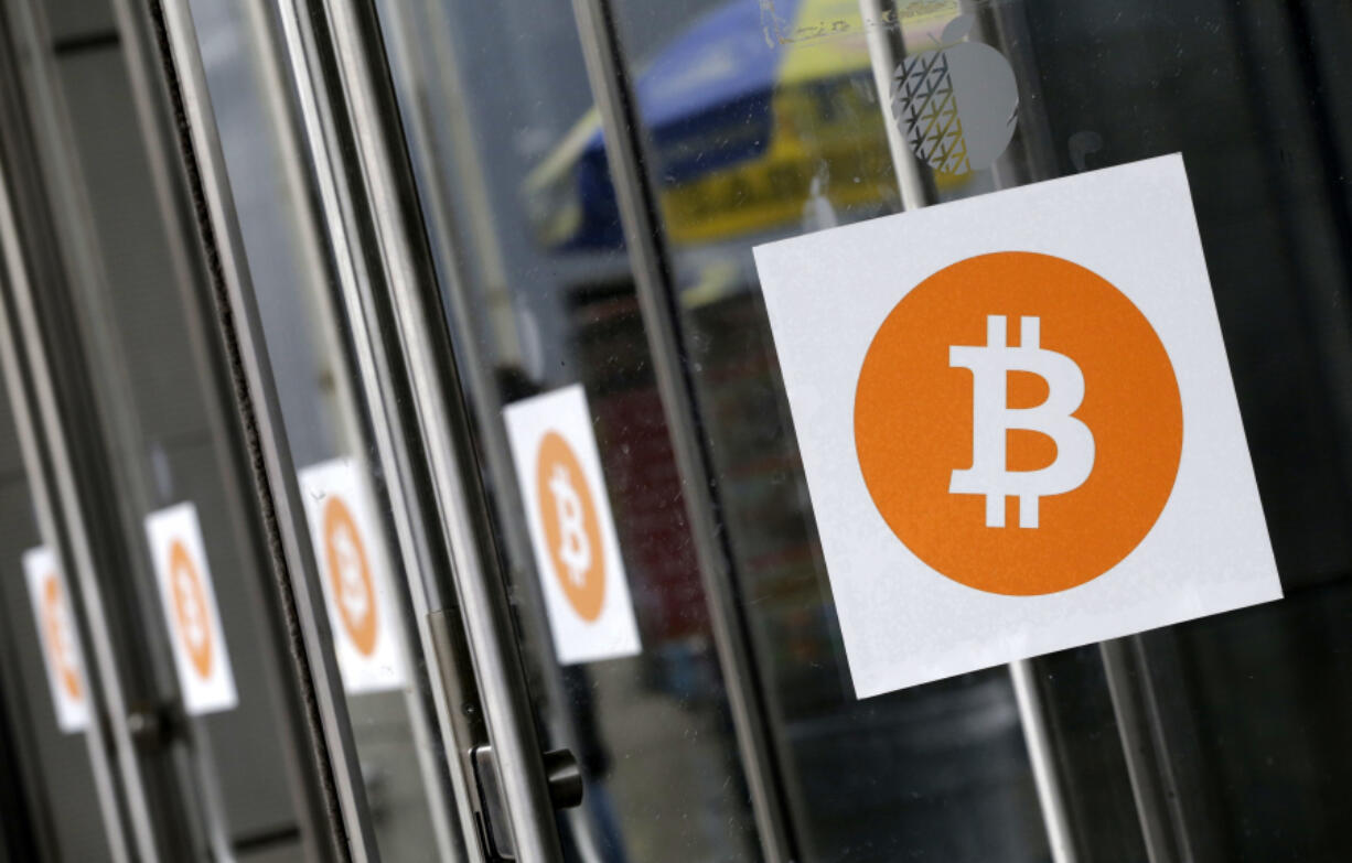 FILE - Bitcoin logos are displayed at the Inside Bitcoins conference and trade show on April 7, 2014, in New York.