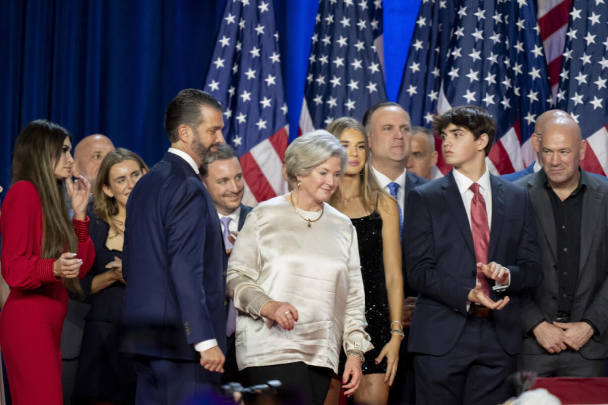 From left, Kimberly Guilfoyle, Tony Fabriozio, Donald Trump Jr., fourth from left, Justin Caporale, Susie Wiles, Kai Madison Trump, Dan Scavino, Corey Lewandowski, Donald Trump III and Dana White listen as Republican presidential nominee former President Donald Trump speaks at an election night watch party Wednesday, Nov. 6, 2024, in West Palm Beach, Fla.