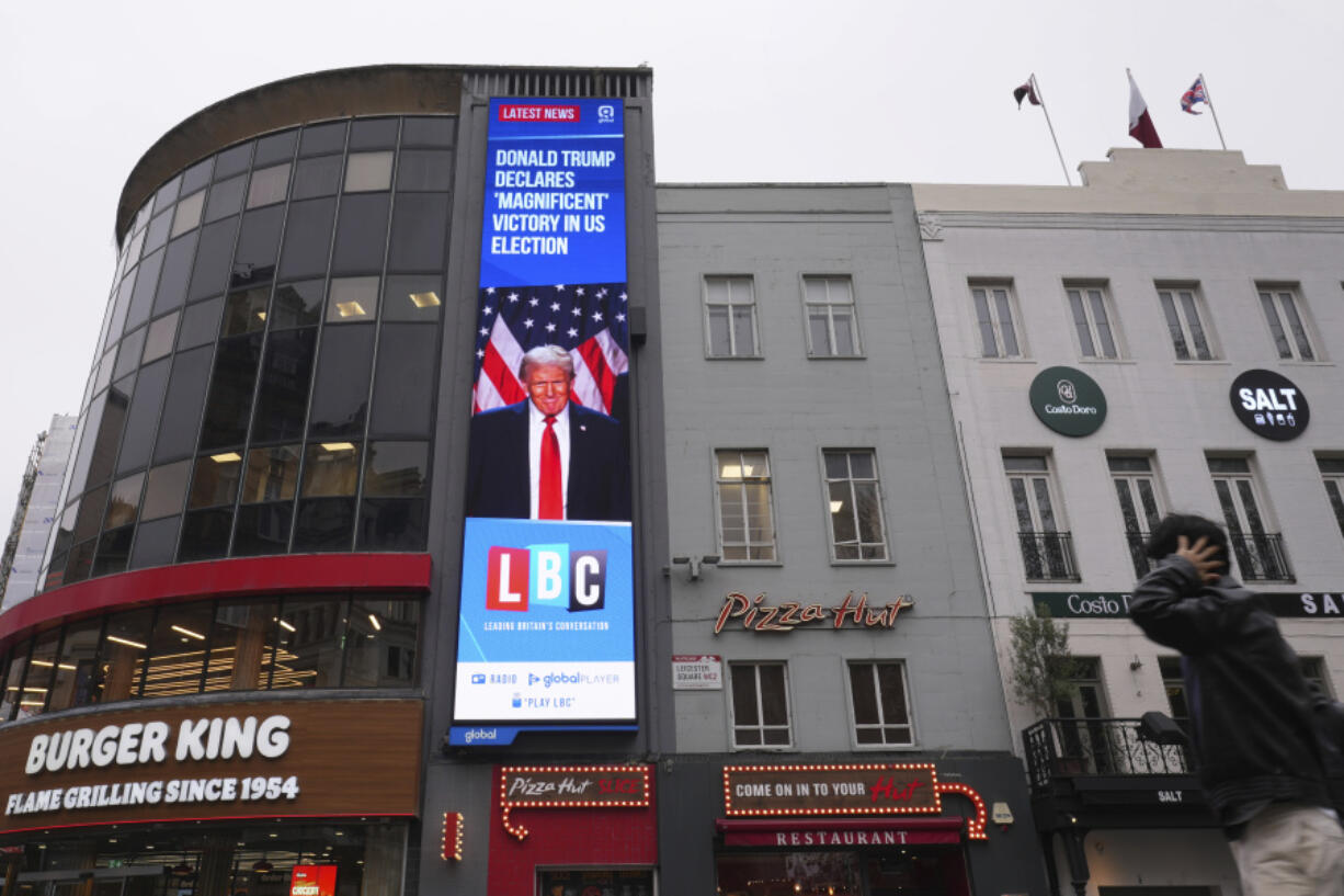 A pedestrian passes a digital screen showing news headlines about the U.S. election, in Leicester Square, London, Wednesday, Nov. 6, 2024.