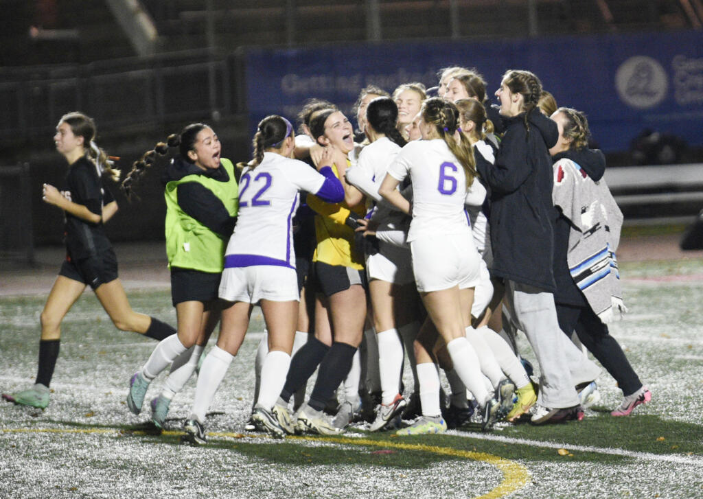 Columbia River players mob goalkeeper Ruby Ayers (facing, in yellow jersey) after the Rapids' 1-0 (3-2 penalty kicks) shootout victory over West Valley of Spokane in Friday's Class 2A girls soccer state semifinal at Mount Tahoma Stadium on Nov. 22, 2024.