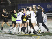 Columbia River players mob goalkeeper Ruby Ayers (facing, in yellow jersey) after the Rapids' 1-0 (3-2 penalty kicks) shootout victory over West Valley of Spokane in Friday's Class 2A girls soccer state semifinal at Mount Tahoma Stadium on Nov. 22, 2024.