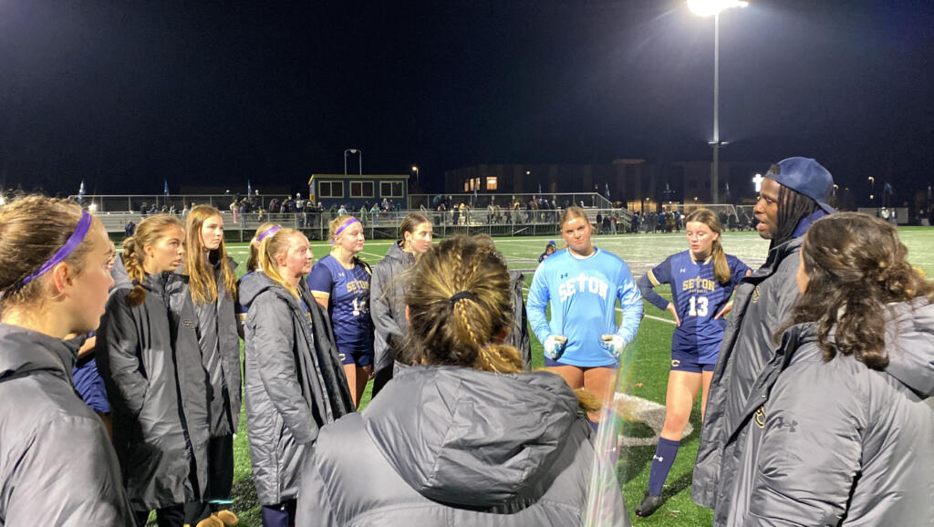 Seton Catholic girls soccer coach Antonio Buckley (right, in hat) addresses the Cougars after their 4-0 shutout of Elma in Thursday's 1A District IV winner-to-state match. The win sends Seton to Saturday's district title match.