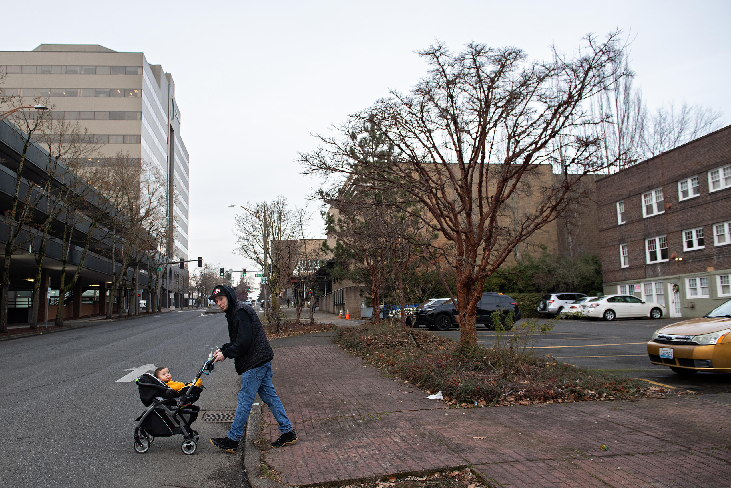 Clint Phillips, resident of Normandy Apartments, right, takes a break with his 10-month-old son, Jayden, in downtown Vancouver on Tuesday afternoon, Dec. 10, 2024. The I-5 bridge expansion could impact several properties, and tenants at Normandy apartments say this is the only truly affordable rent in the city.