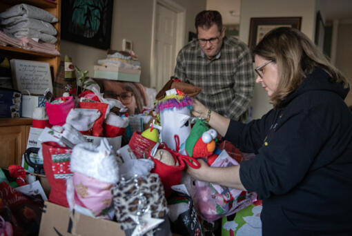 Matt Griffin, left, and Melinda Griffin on Thursday look over gift packages in honor of their daughter, Maddy, pictured at left, who died of brain cancer in 2022. They now honor their daughter with a Facebook page called &ldquo;Miracle Maddy,&rdquo; where they advocate for spreading awareness of childhood cancers. Every holiday season, the Griffin family makes goodie baskets for pediatric oncology patients.