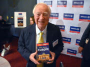 Guidebook author and publisher Arthur Frommer holds up his latest book Nov. 18, 2015, &ldquo;Arthur Frommer&rsquo;s Europe,&rdquo; in New York.