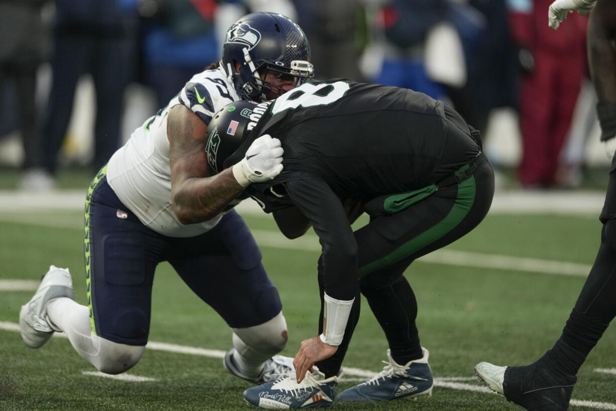 Seattle Seahawks defensive end Leonard Williams (99), left, sacks New York Jets quarterback Aaron Rodgers (8) during the second half of an NFL football game, Sunday, Dec. 1, 2024, in East Rutherford, N.J.