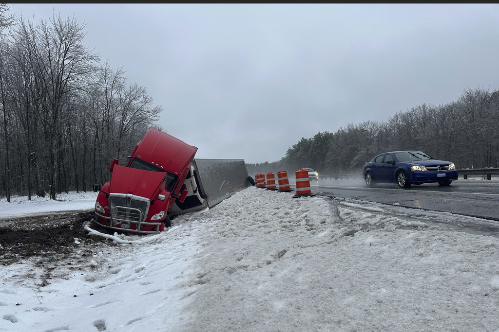 A tractor-trailer hauling a load of oranges sits on the side of the road after sliding off the Maine Turnpike early on Wednesday, Dec. 11, 2024, in New Gloucester, Maine.