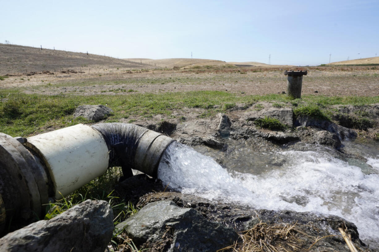 FILE - Well water flows from pumps into a canal that will be used to irrigate a vineyard, Monday, July 25, 2022, in Rio Vista, Calif.