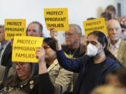 People hold signs during a San Diego County board of supervisors meeting Tuesday, Dec. 10, 2024, in San Diego.