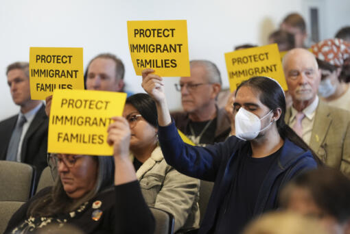 People hold signs during a San Diego County board of supervisors meeting Tuesday, Dec. 10, 2024, in San Diego.