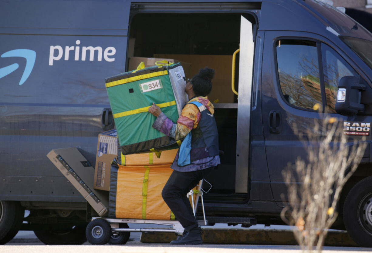 FILE - An Amazon Prime delivery person lifts packages while making a stop on Nov. 28, 2023, in Denver.