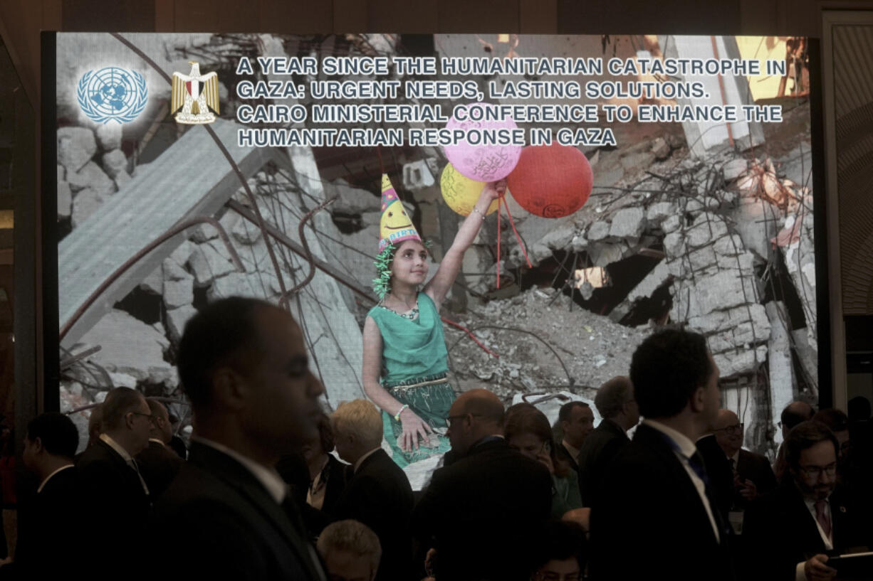 Participants at the Cairo Ministerial Conference to Enhance the Humanitarian Response in Gaza, walk under a screen displaying an image from Gaza before their meeting in Cairo, Egypt, Monday, Dec. 2, 2024.