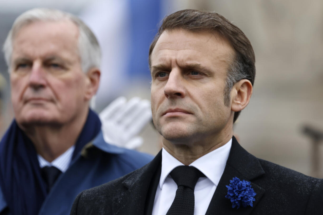 FILE - French President Emmanuel Macron, right, and Prime Minister Michel Barnier stand at attention during commemorations marking the 106th anniversary of the November 11, 1918, Armistice, ending World War I, at the Arc de Triomphe in Paris, Monday, Nov. 11, 2024.