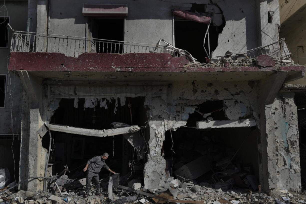 Ali Haidous, removes the debris from his destroyed butcher shop after he returned with his family to his village of Hanouiyeh, southern Lebanon, Thursday, Nov.