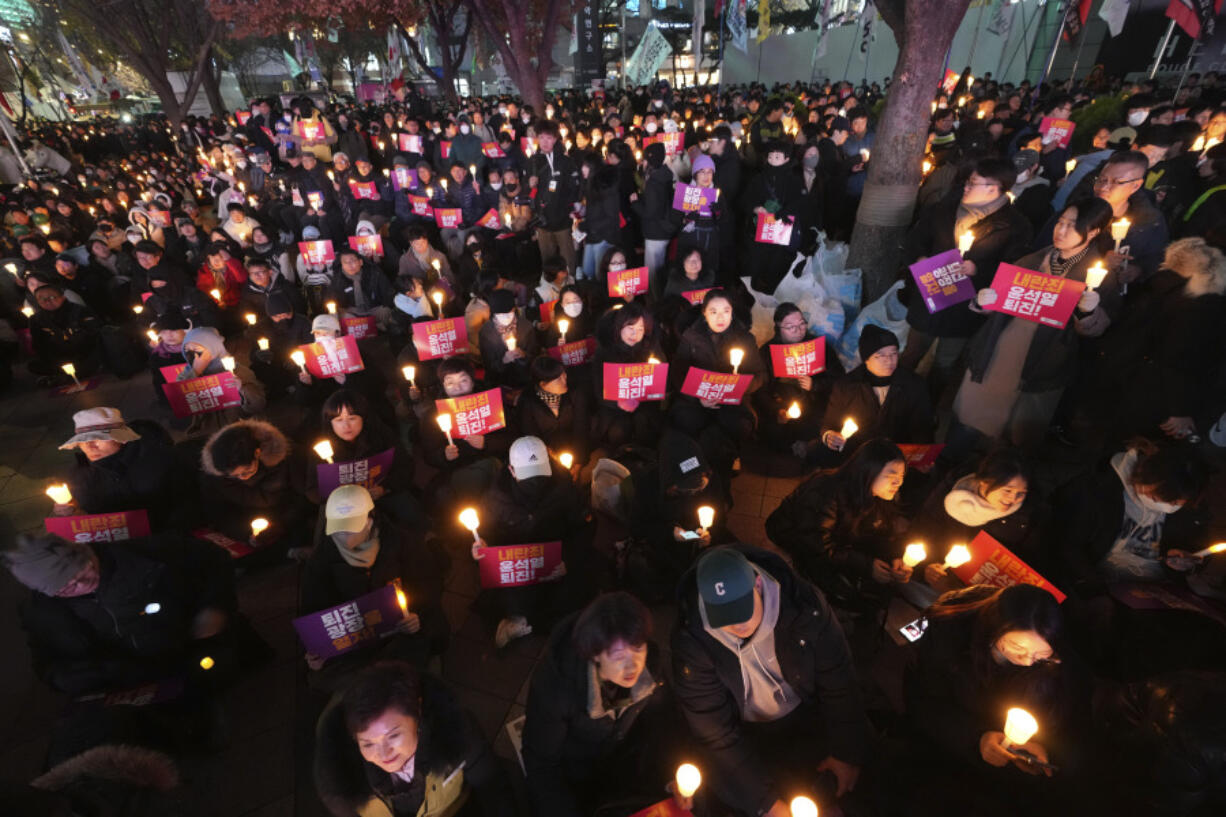 People hold candles during a candlelight vigil against South Korean President Yoon Suk Yeol in Seoul, South Korea, Wednesday, Dec. 4, 2024.