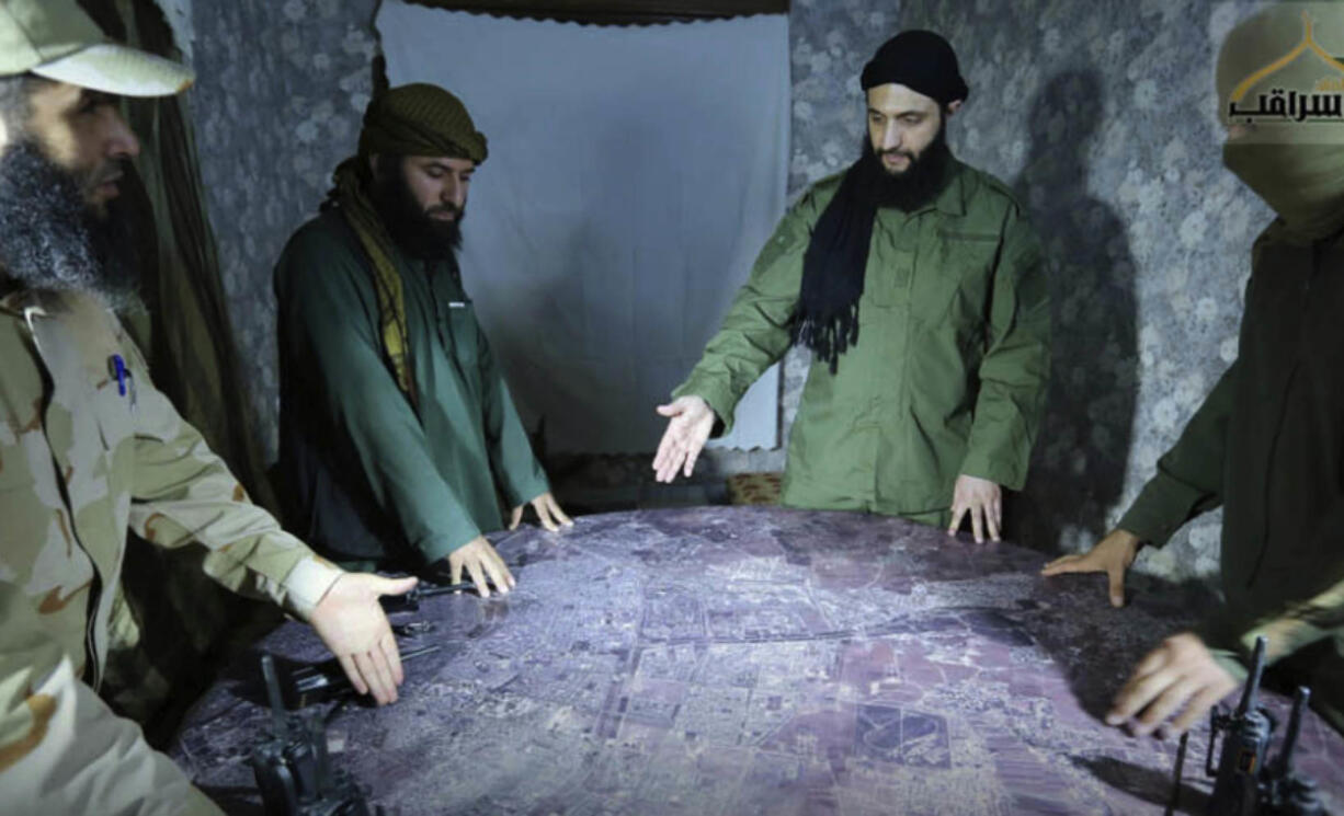 FILE - This undated file photo released by a militant group in 2016, shows Abu Mohammed al-Golani of the militant Levant Liberation Committee and the leader of Syria&rsquo;s al-Qaida affiliate, second right, discussing battlefield details with field commanders over a map, in Aleppo, Syria.