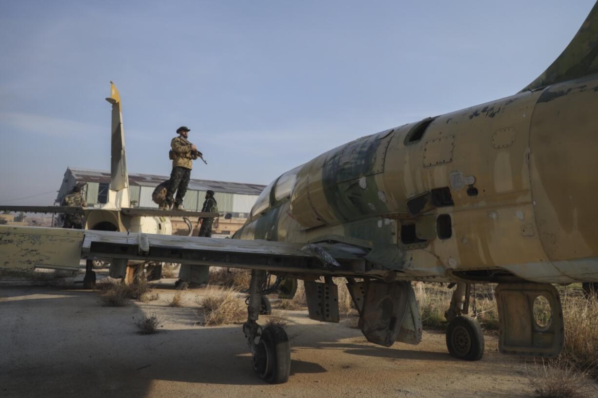 Syrian opposition fighters stand on the wings of an old aircraft at the Al-Nayrab military airport after they took control of the facility in the outskirts of Aleppo, Syria, Monday, Dec. 2, 2024.