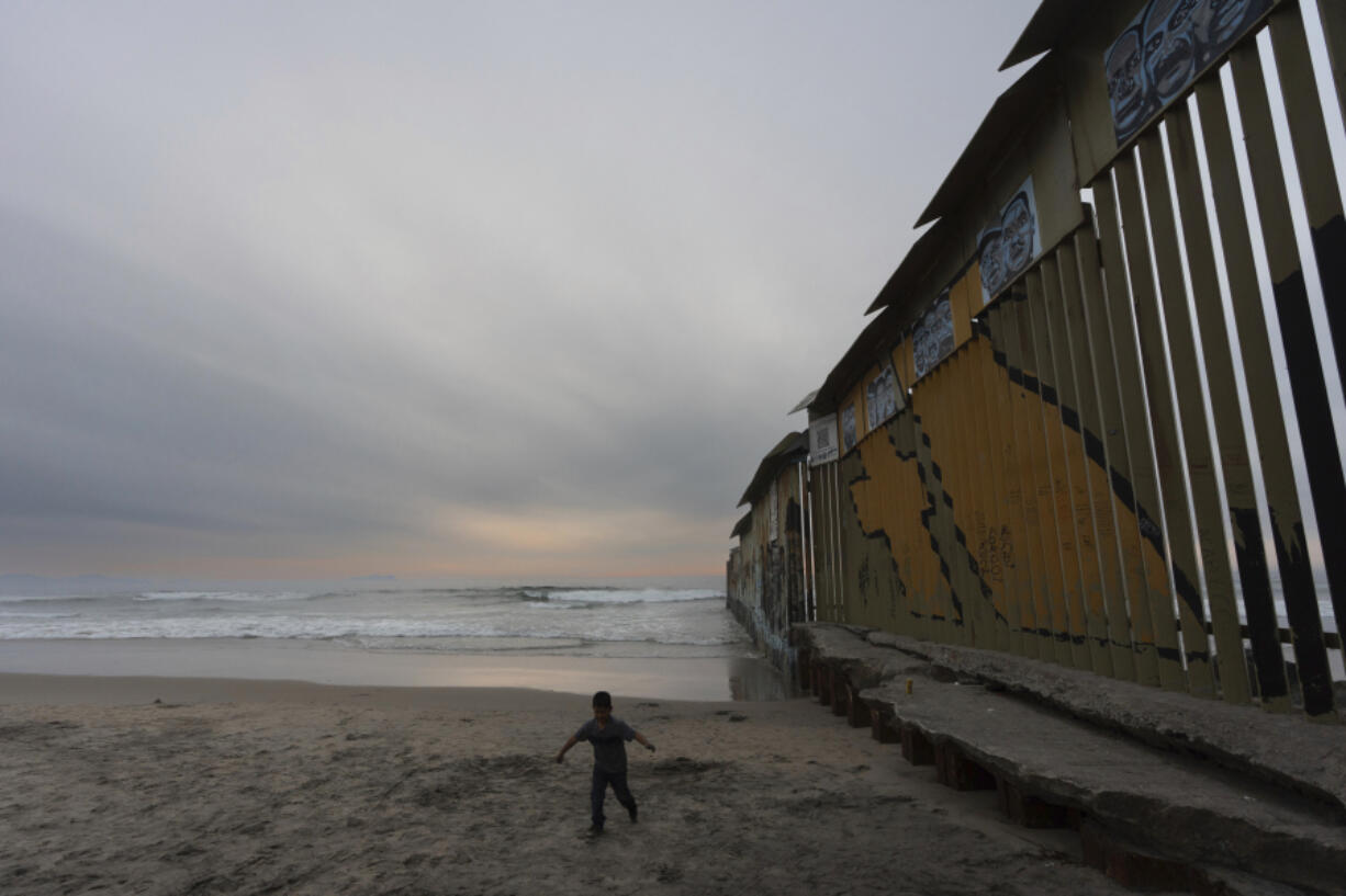 A boy walks near where a border wall separating the United States from Mexico reaches the Pacific Ocean, Tuesday, Nov. 26, 2024, in Tijuana, Mexico.