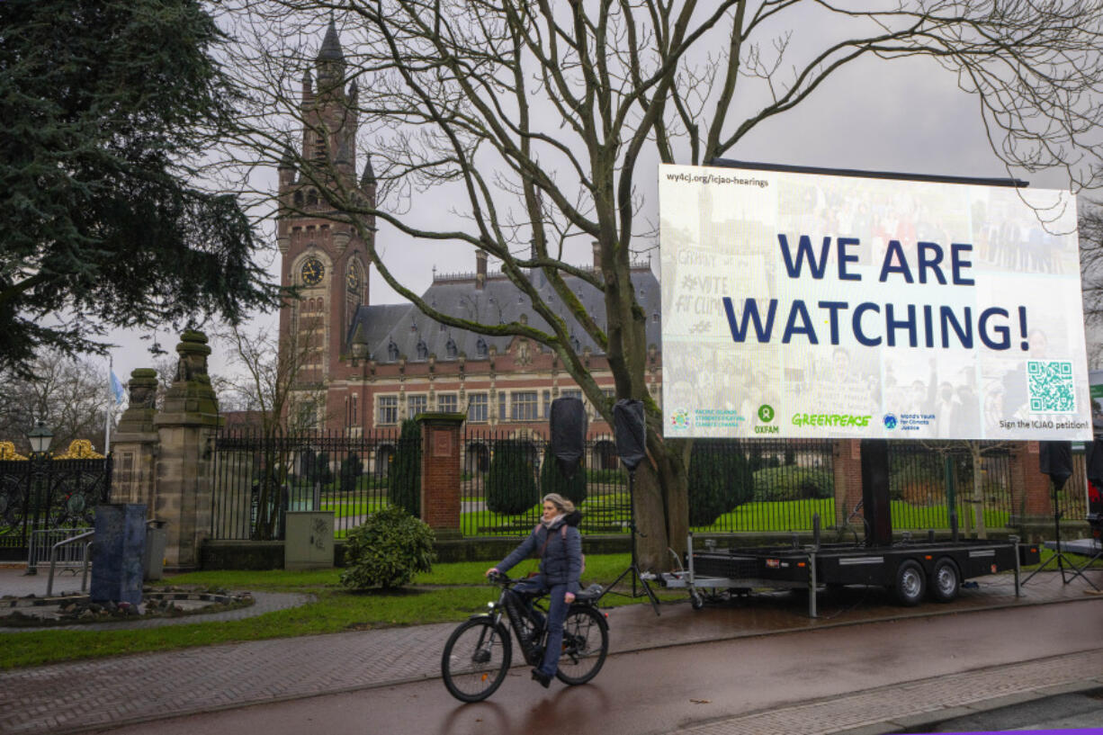 Activists put up a billboard outside the International Court of Justice, in The Hague, Netherlands, as it opens hearings into what countries worldwide are legally required to do to combat climate change and help vulnerable nations fight its devastating impact, Monday, Dec. 2, 2024.