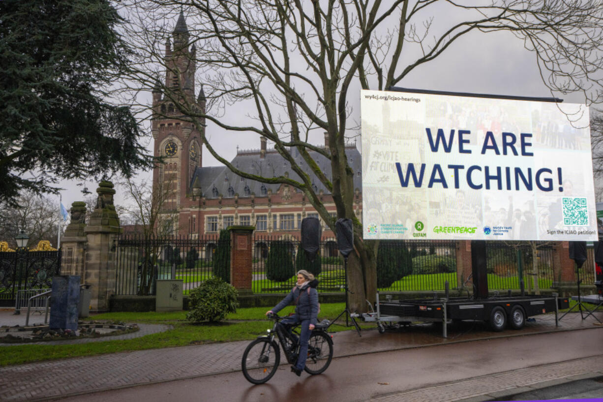 Activists put up a billboard outside the International Court of Justice, in The Hague, Netherlands, as it opens hearings into what countries worldwide are legally required to do to combat climate change and help vulnerable nations fight its devastating impact, Monday, Dec. 2, 2024.